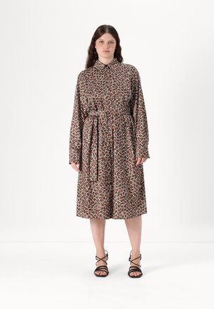 Brun og hvit langermet kjole med blomstermønster, belted midje og knapper under kragen. Kledd sammen med svarte sandaler med stropper.