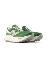 Une paire de chaussures de trail New Balance vertes et blanches avec des semelles texturées et des semelles intermédiaires Fresh Foam, angulées à droite sur un fond blanc.