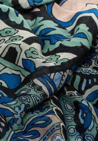 Tissu à motifs bleus et verts avec des dessins floraux, une texture tissée et des contours noirs contrastants, présentant des qualités de drapage souple.