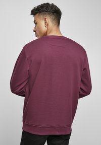 Bordeaux hettegenser med rund hals, lange ermer og ribbede mansjetter, med en myk tekstur og komfortable passform. Ingen fremtredende design detaljer.