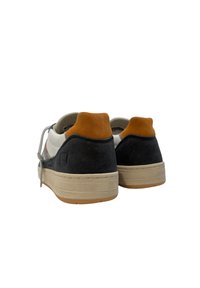 Sneakers con design a materiali misti che includono suede nero, lati in pelle bianca e tallone in suede marrone. Suola piatta in gomma. Lacci grigi.