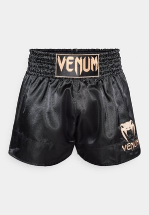 Pantaloncini da boxe in satin nero con vita elastica. Presentano il logo "VENUM" dorato e un emblema a forma di ragno sul lato. Tessuto liscio, vestibilità regolare.