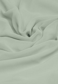 Hellgrüner Chiffonstoff mit einer sanften, fließenden Textur, die zarte Falten und Fältchen zeigt, welche die Leichtigkeit des Materials betonen.