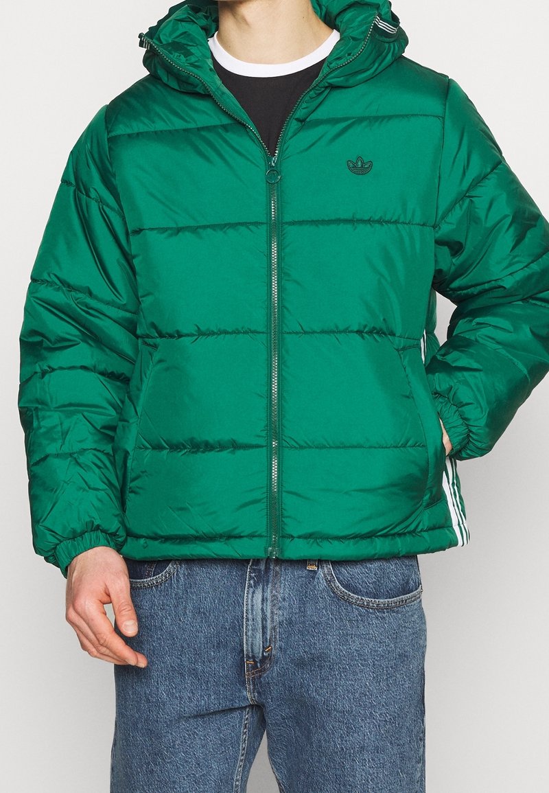 Zelená péřová bunda s předním zipem, elastickými manžetami a dvěma postranními kapsami. Obsahuje kapuci a bílé logo Adidas na hrudi.