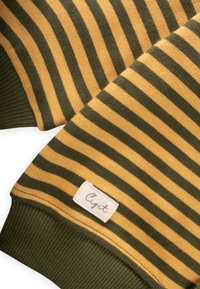 Pruhovaný sveter s olivovou zelenou a horčicovo žltou farbou, s rebrovanými manžetami a textilnou etiketou s nápisom "Cigit" na leme.