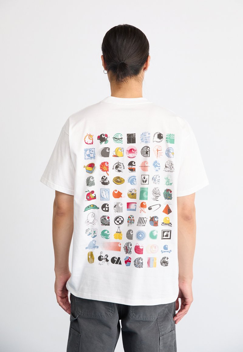 Camiseta blanca de algodón con diversos gráficos coloridos en la parte posterior, incluidos íconos, símbolos e ilustraciones dispuestos en un patrón de cuadrícula.