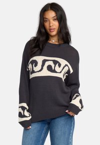 Maglione grigio scuro con un design orizzontale a onde color crema, maniche a coste e scollatura rotonda, realizzato in morbido materiale tricottato.