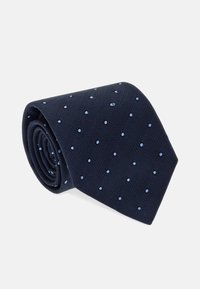 Námořnická kravata vyrobená z texturované látky s světle modrými puntíky. Rolovaný design zd ůrazňuje vzor a materiál.