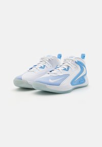 Pantofi sport albi și bleu deschis, cu un superior din plasă, talpă din cauciuc și o marcă proeminentă, având texturi netede și accente de design curbate.
