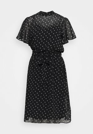 Vestido negro hasta la rodilla con pequeño estampado floral blanco, mangas cortas y transparentes, escote alto y cinturón anudado en la cintura.