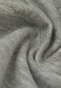 Lichtgrauer Strickstoff zeigt eine weiche Textur mit einem dezenten gerippten Muster und einem sanften, fließenden Fall. Verfügt über feine Nähdetails.