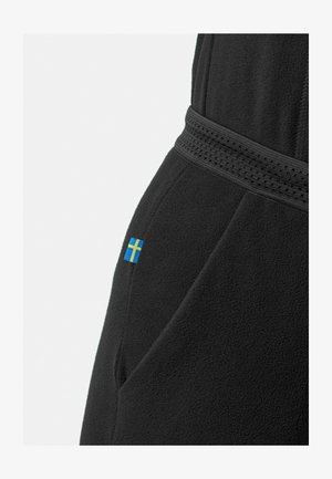 Vêtement en polaire noire avec une ceinture texturée et un petit drapeau suédois brodé sur le côté.