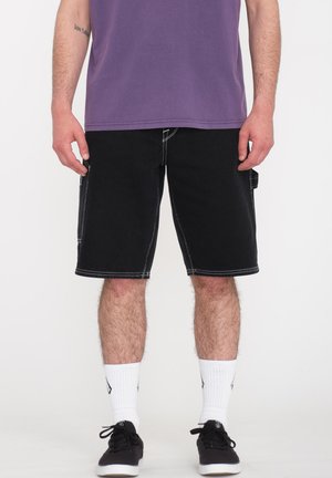 Zwarte denim shorts met witte stiksels, zakken aan de zijkant en een rechte snit. Draag het met een paarse shirt en zwarte sneakers, met witte sokken.