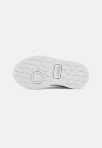Vit sneakersula med ett texturerat greppmönster, cirkulär detalj och präglad logotyp. Slät material med en platt, rundad form.
