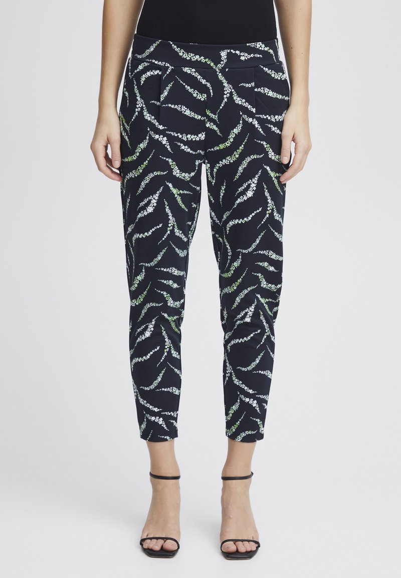 Patterned trousers in navy with white and green abstract designs. Features a slim fit, pleats at the waist, and cropped length.