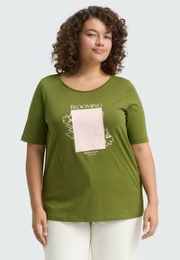Grünes Kurzarm-T-Shirt aus weichem Stoff, mit einem floralen Design und dem Text "BLOOMING" in Weiß sowie einem pinken Akzentquadrat.