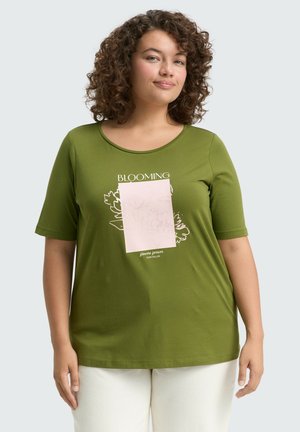 T-shirt vert à manches courtes en tissu doux, avec un motif floral et le texte "BLOOMING" en blanc sur un carré rose.
