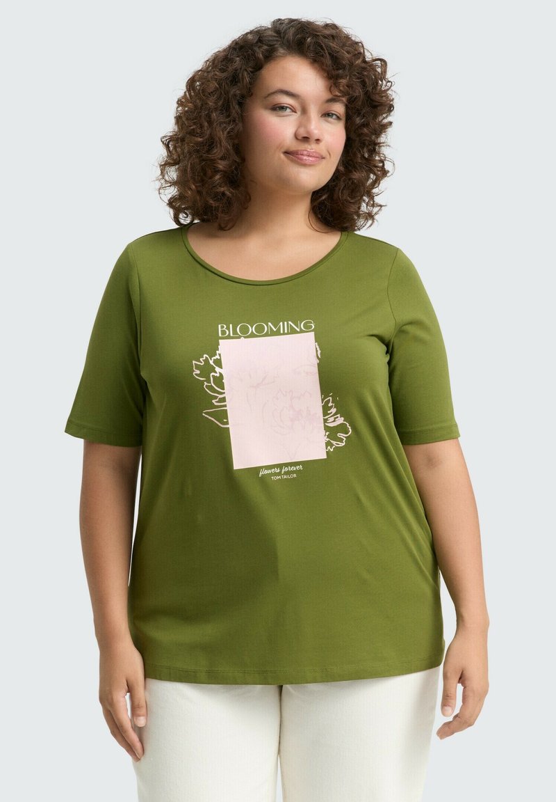 Grünes Kurzarm-T-Shirt aus weichem Stoff, mit einem floralen Design und dem Text "BLOOMING" in Weiß sowie einem pinken Akzentquadrat.