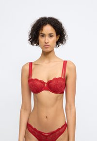Rød blonde-BH med blomsterdesign, underwire støtte, og smale justerbare stropper. Inkluderer en liten gulldetalj i midten.