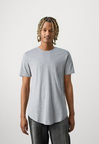 Grijze t-shirt met korte mouwen van gladde stof, met een ronde hals en een gebogen zoom, gedragen met een donkere spijkerbroek.