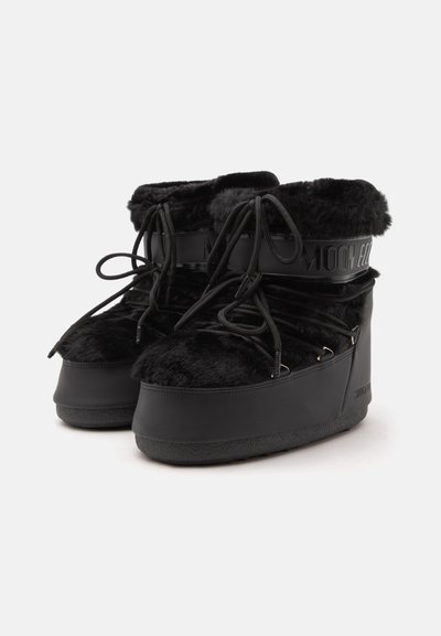 Paire de bottes d'hiver noires doublées en fourrure, avec semelles épaisses et laçage à l'avant, dotées d'une sangle de marque autour de la cheville.