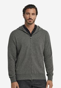 Grå zip-up hoodie med huva, tillverkad av texturerad tyg, som har sidofickor och ribbade muddar vid handlederna och nederkanten.