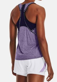 Lila sportlinne med texturerad gradientdesign, utrustad med racerback och kontrasterande branding. Matchas med vita shorts.