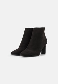 Botines de ante negros con punta afilada y un tacón de bloque de 5 cm. Textura suave, sin hardware visible ni patrones.