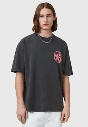 Grijze oversized t-shirt gemaakt van katoen, met korte mouwen en een roze grafisch logo op de linkerborst. Gladde textuur, casual fit.