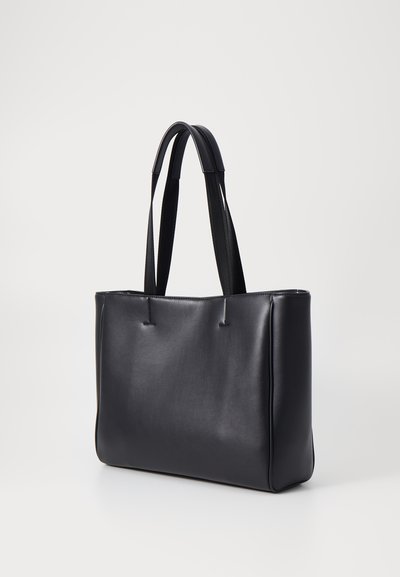 Sac fourre-tout en cuir noir avec une texture lisse, une forme structurée et deux poignées. Présente une couturière minimaliste et un design sans couture.