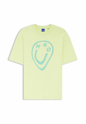 Camiseta de manga corta de color verde claro con un gráfico abstracto azul de una cara sonriente y el texto "HUGO", con una etiqueta de marca azul en el cuello.