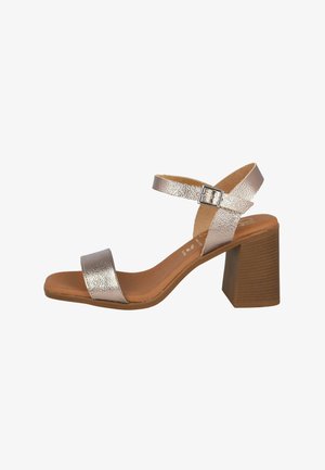 Sándal de tacón alto plateado metálico con parte superior texturizada, punta abierta, correa en el tobillo con hebilla y tacón cuadrado marrón. Plantilla suave.