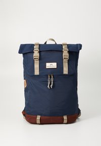 Marineblå ryggsekk med rull-topp design, beige stropper og maskinvare, brun bunnaccent, doble glidelåser og merkelapp foran.