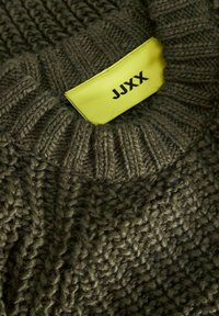 Donkergroene gebreide trui met een gestructureerd patroon; heeft een geribbelde kraag en een felgele label met de tekst "JJXX."