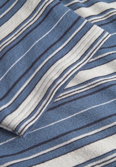 Tissu tricoté en rayures bleues, blanches et bleu marine avec une surface texturée. Le tissage a un poids moyen, adapté à un usage décontracté.