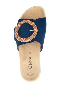 Navy blue suede slide sandal with a circular wooden bead accent and metal pin, featuring a cork footbed for added comfort.
