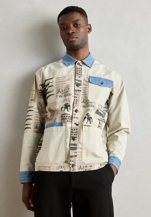 Light beige jacket with denim collar and cuffs, featuring graphic prints, large front pockets, and button closures.