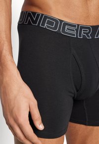 Fekete pamut boxer alsónemű vastag derékrésszel, melyen a "UNDER" felirat szürke színben szerepel. Szoros illeszkedésű dizájn, funkcionális elülső nyílással.