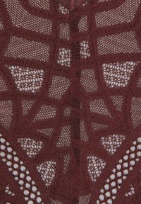 Burgunderfarbener Spitze-Stoff mit geometrischem Muster, der offene Webarten und strukturierte Akzente aufweist. Das Design enthält aufwendige Stickereien und einen reflektierenden Faden.