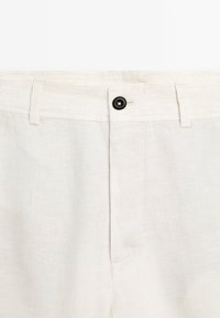 Linnen broek in lichtbeige met een sluiting aan de voorkant, voorzien van een soepele textuur en subtiele stiksels, ontworpen voor comfort en ademend vermogen.