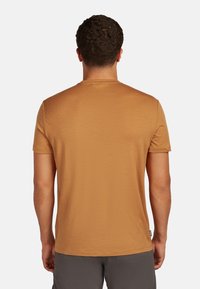 Camiseta de manga corta y cuello redondo en un color marrón claro. Textura suave, diseño sencillo y sin patrones o acentos visibles.