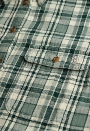 Koszula flanelowa w zielono-kremową kratę, z guzikami, dwoma kieszeniami na piersi oraz miękką fakturą o splocie jodełkowym.
