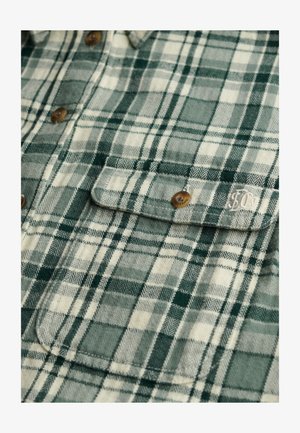 Koszula flanelowa w zielono-kremową kratę, z guzikami, dwoma kieszeniami na piersi oraz miękką fakturą o splocie jodełkowym.