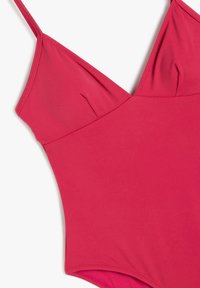Bañador de una pieza de color rosa brillante, hecho de una tela suave, con tirantes ajustables, un escote en V y un diseño entallado que favorece.