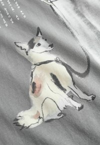 Grafika na šedej látke s ilustráciou psa vo vodovom štýle, zobrazuje biele telo s čiernymi a hnedými škvrnami.