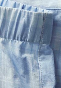 Tissu bleu clair avec une ceinture élastique et des coutures visibles, probablement partie d'un vêtement tel que des shorts ou un pantalon.