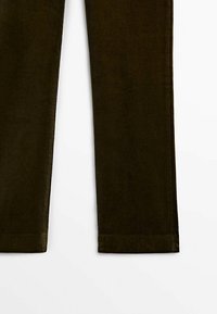 Jambes de pantalon en velours côtelé vert foncé, coupe droite, rainures verticales visibles et ourlets sur fond blanc.