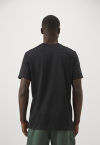 Sort bomulds T-shirt med korte ærmer og rund hals. Stoffet ser blødt ud med en glat tekstur og har et enkelt og klassisk design.
