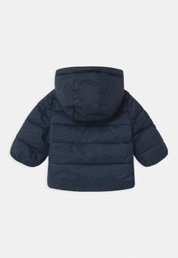 Námořnická modrá pufovaná bunda pro batolata s kapucí, která má malé černé puntíky a horizontální prošívání na zadní části a rukávech.