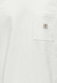 Witte katoenen t-shirt met een borstzak en een vierkante logo patch. Zachte textuur en eenvoudig ontwerp.